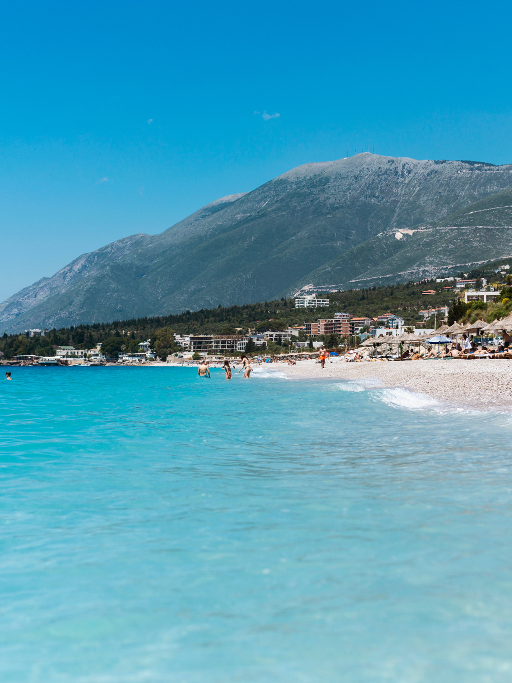 Albānijas piekraste ar tirkīzzilu jūru un kalniem fonā, pludmale